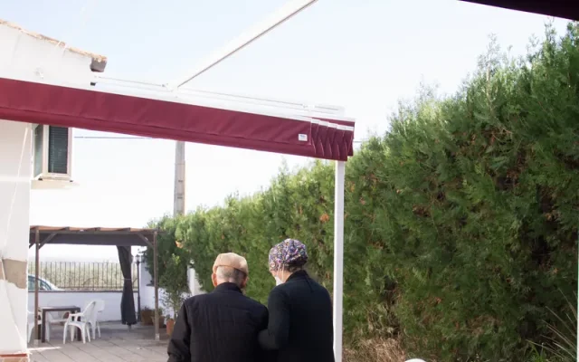 Familiar paseando con una persona mayor por el patio de una residencia