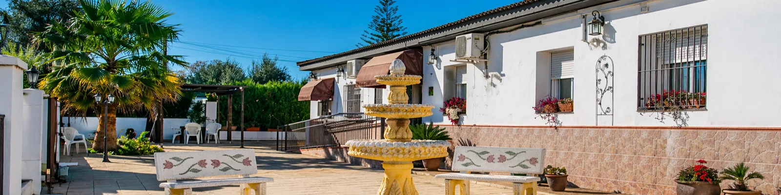 Patio del Centro de Mayores Fuenteclara en Palomares del Río, con fuente y zona de estar al aire libre
